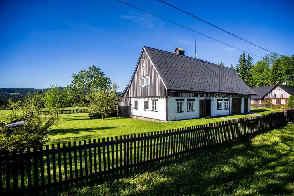 a white house with a black roof and a fence at Chalupa Přeslička in Rejvíz