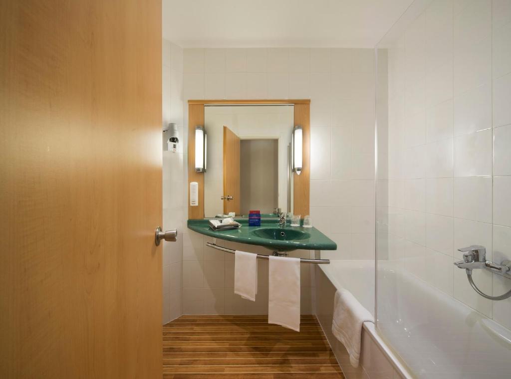 W łazience znajduje się umywalka, lustro i wanna. w obiekcie Hotel Rafael w Mediolanie