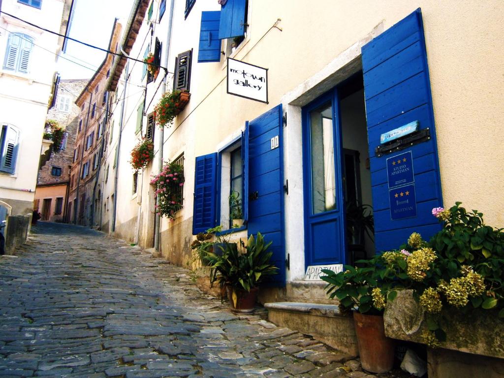 an alley with blue shutters on a building at Apartments Galerija Motovun in Motovun