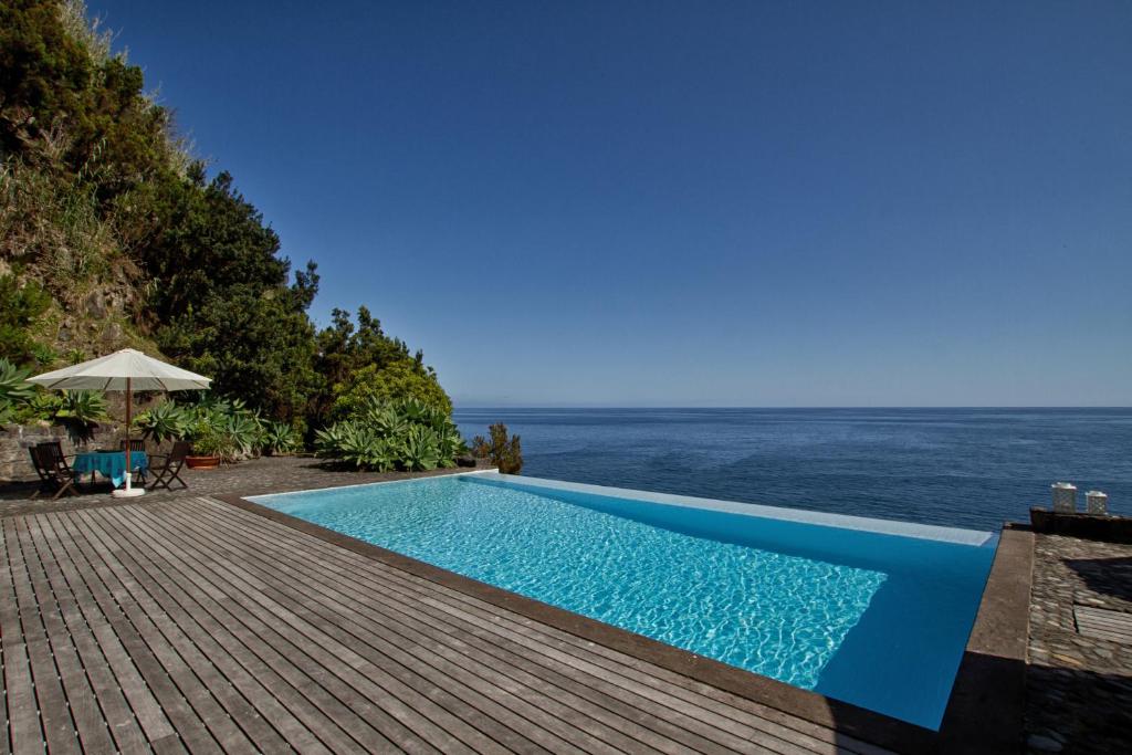 a swimming pool with a view of the ocean at Casa de Pedra in Ribeira Quente