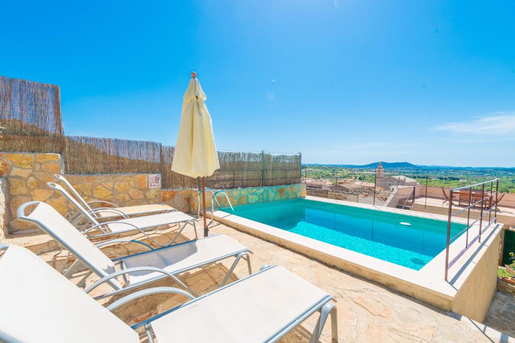 a villa with a swimming pool with chairs and an umbrella at Sa Casa De Ses Bicicletes in Caimari