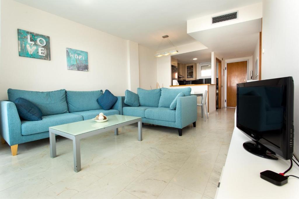 ein Wohnzimmer mit blauen Sofas und einem TV in der Unterkunft Central park Blanes in Blanes