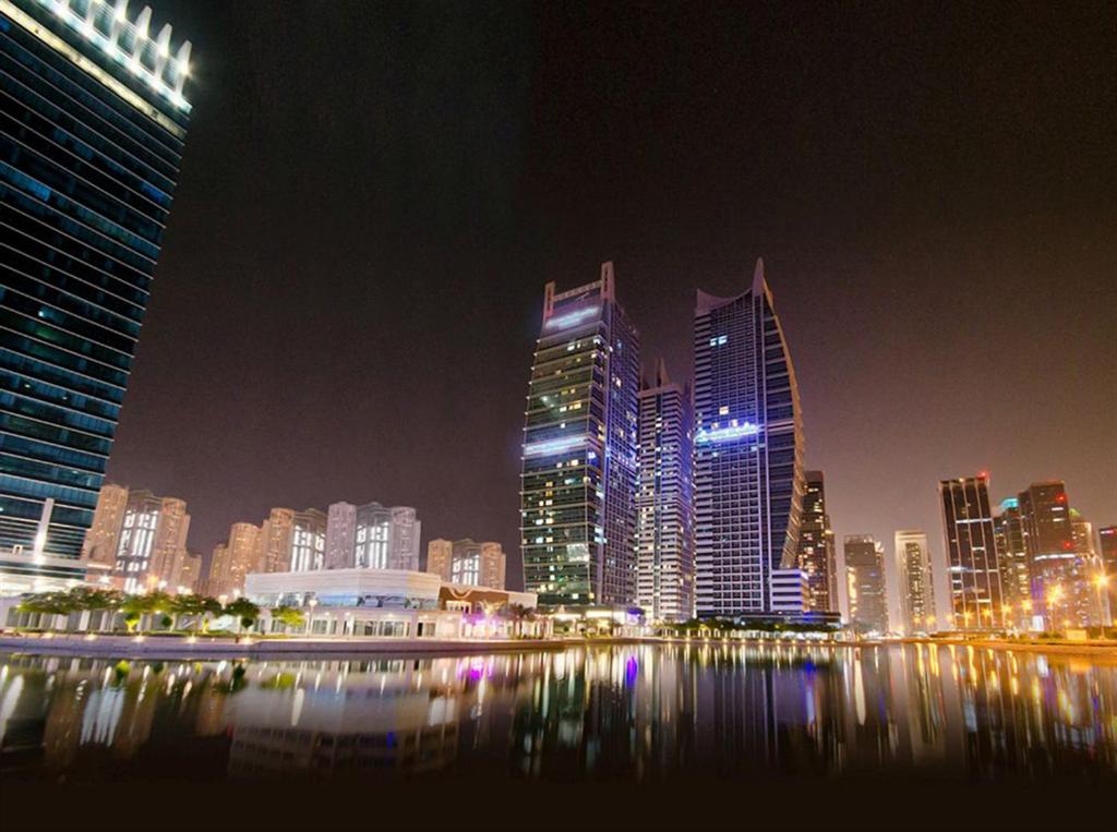 a city skyline at night with tall buildings at Armada Living - Holiday Homes Rental in Dubai