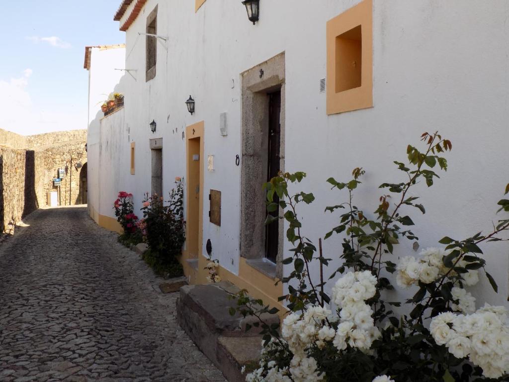 un callejón empedrado con flores y edificios blancos en Casa O Arco Alojamento Local en Marvão