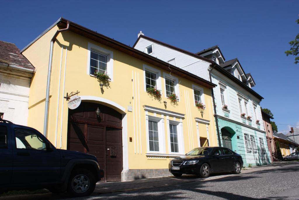 a yellow house with a car parked in front of it at Pension Anna in Veľká Lomnica