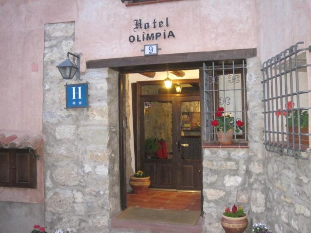 una puerta delantera de un edificio con un cartel en Hotel Olimpia en Albarracín