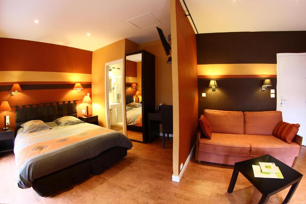 a bedroom with a bed and a couch and a mirror at Hostellerie De La Mer in Crozon