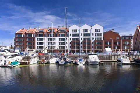 a group of boats docked in a marina with a building at Apartamenty Apartinfo Szafarnia in Gdańsk