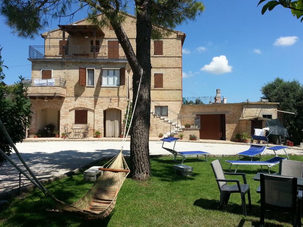 una casa con un árbol y hamacas delante en Agriturismo Galanti, en Cossignano