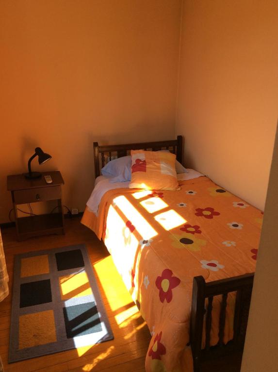 a bedroom with a bed with a floral comforter at Hostal Brisas del Sur in Temuco