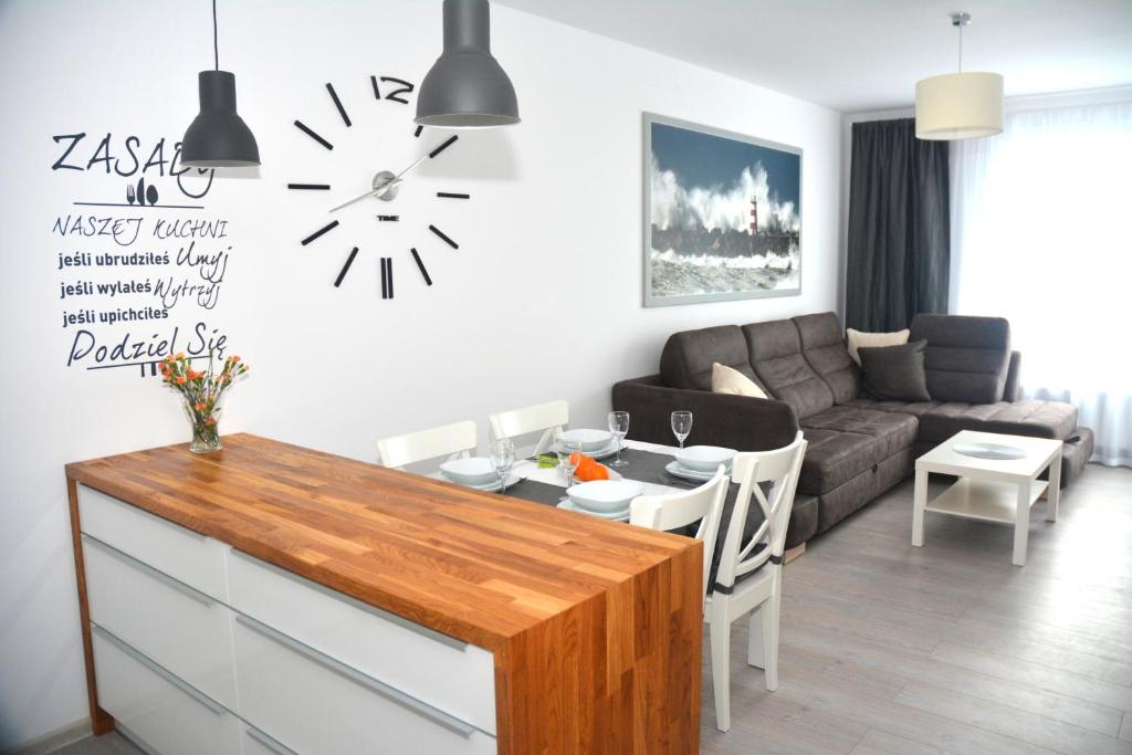 ein Wohnzimmer mit einem Sofa und einer Uhr an der Wand in der Unterkunft Apartament Solna 11 in Kołobrzeg