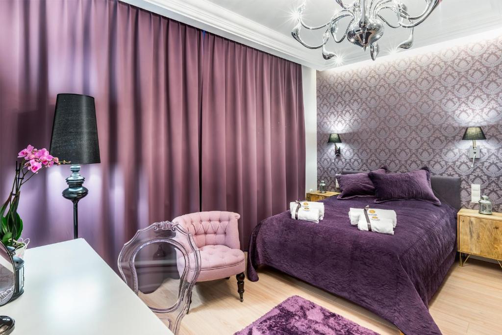 ソポトにあるSea Sail Apartmentsの紫色のベッドルーム(ベッド1台、椅子付)