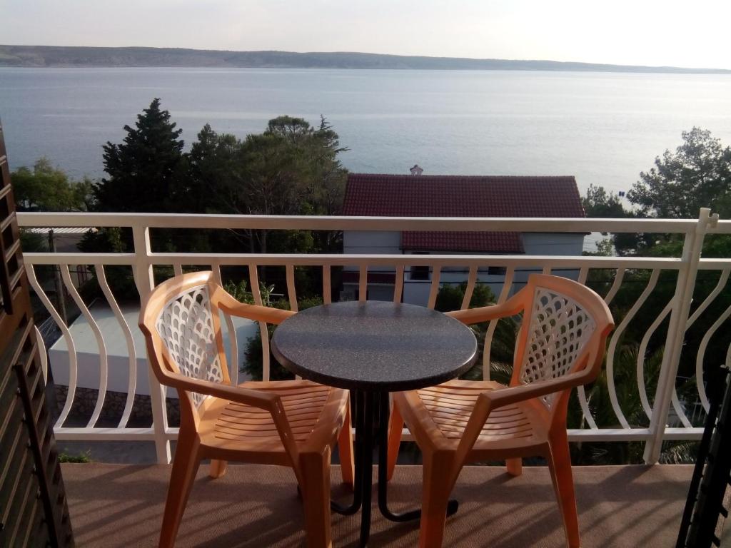 a table and chairs on a balcony with a view of the water at Apartments Ivanka in Starigrad