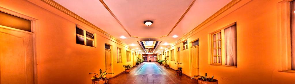 un pasillo con paredes de color naranja y un largo pasillo con plantas en Hotel Monserrat, en Cochabamba