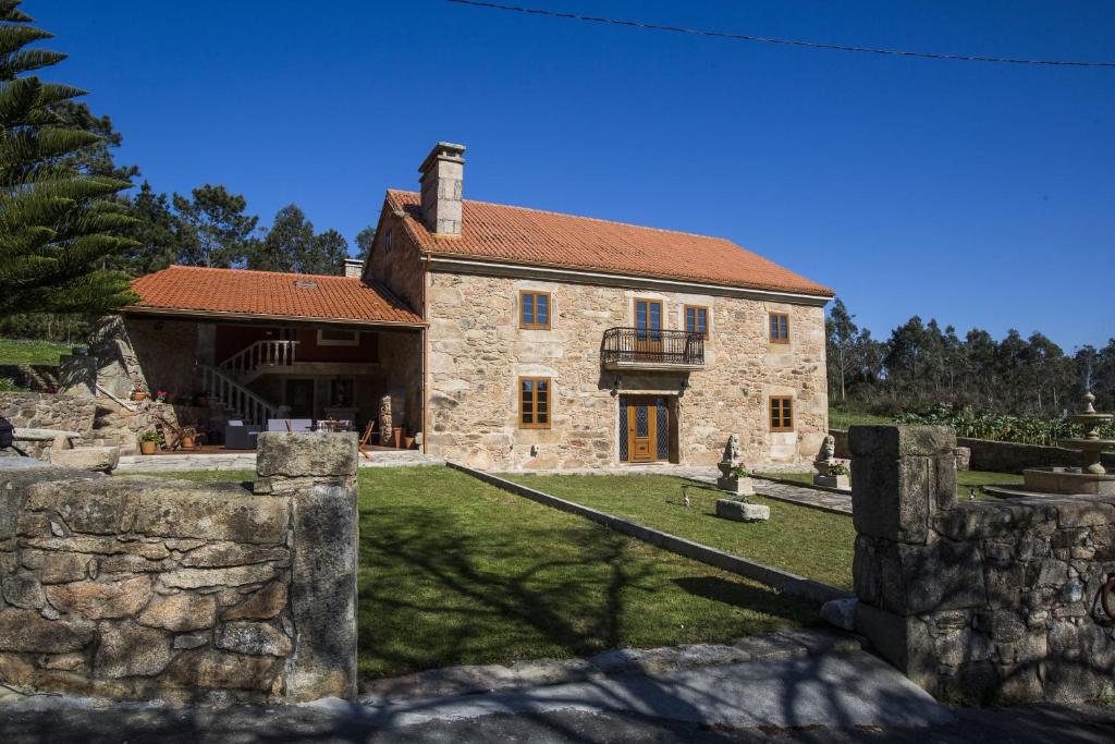 una antigua casa de piedra con una pared de piedra en A Casa da Gandara en Camariñas