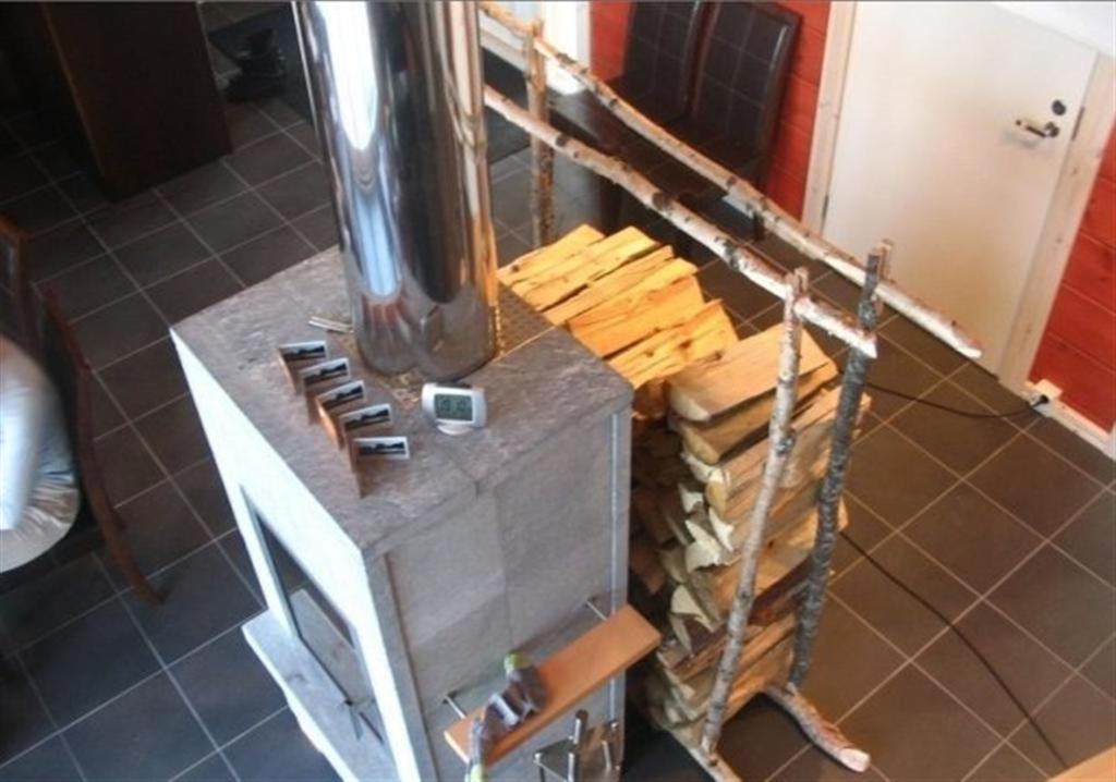 una estufa en una cocina con una pila de madera en Koitelin Residenssi en Oulu