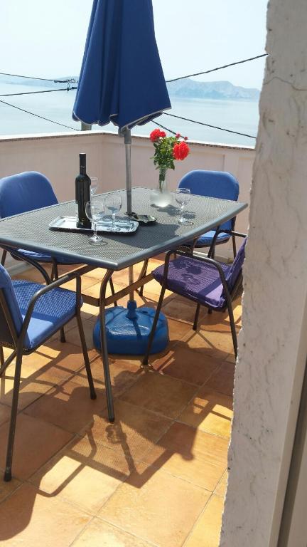 a table with blue chairs and a blue umbrella at Apartments Lucic in Senj