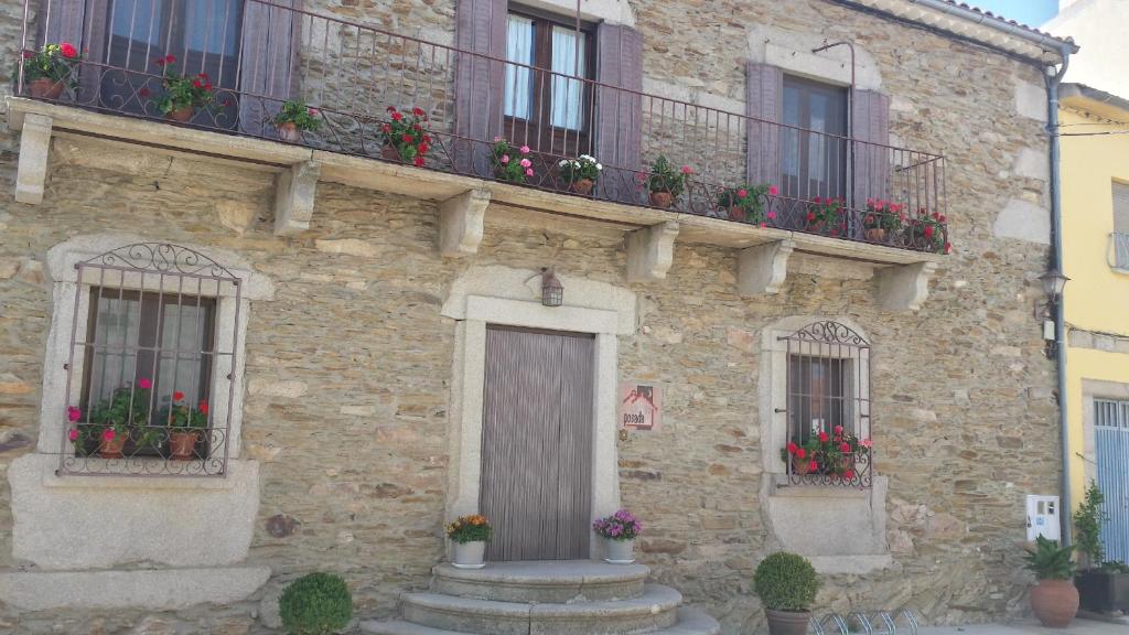 um edifício de pedra com caixas de flores e janelas em Posada de Los Aceiteros em Ahigal de los Aceiteros