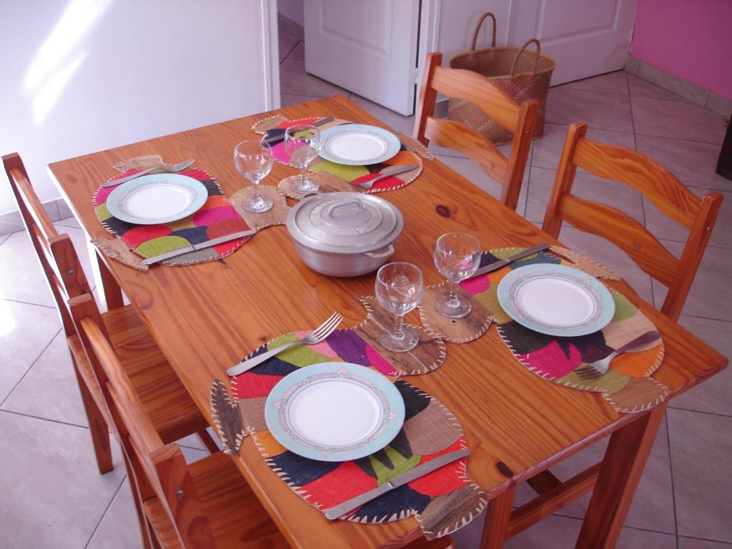 a wooden table with plates and wine glasses on it at villa les Grenadines in Entre-Deux