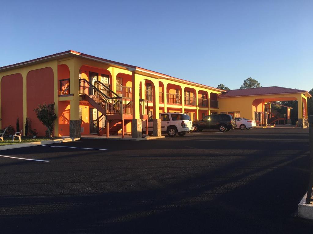 a building with cars parked in a parking lot at Relax Inn McRae in McRae