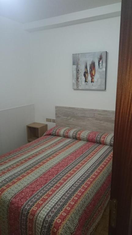 een bed met een gestreept dekbed in een slaapkamer bij Bahia de Chapela in Redondela
