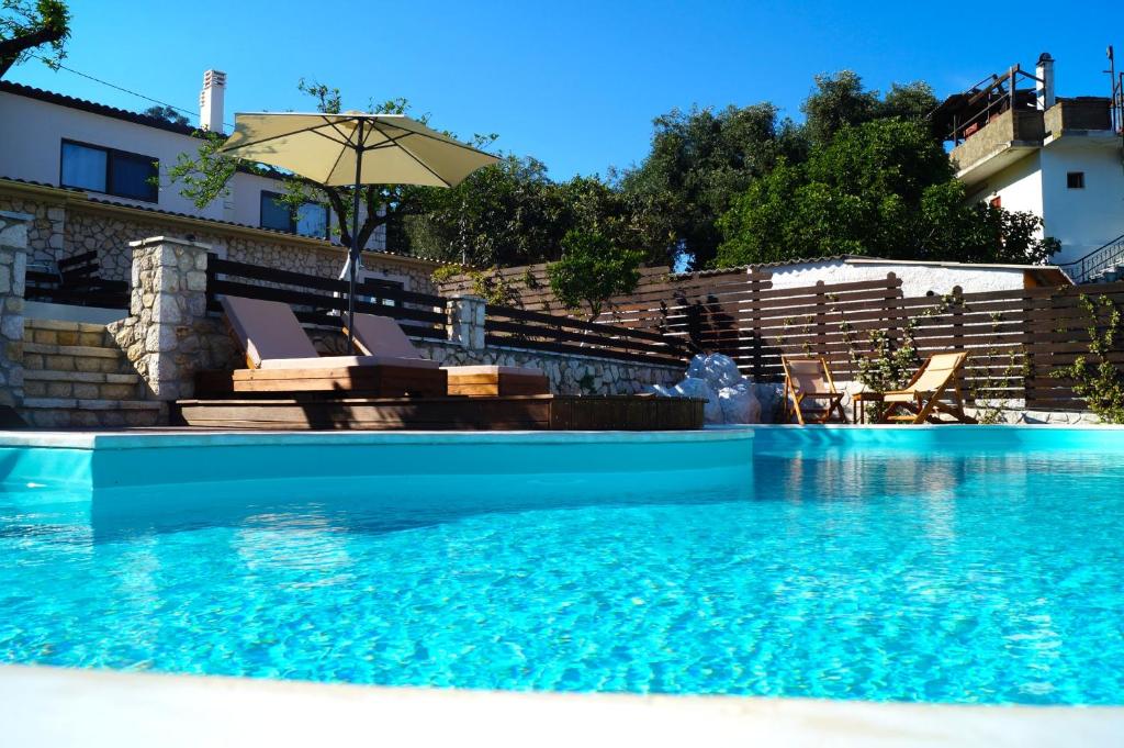 uma piscina com duas cadeiras e um guarda-sol em Anita Village em Perama