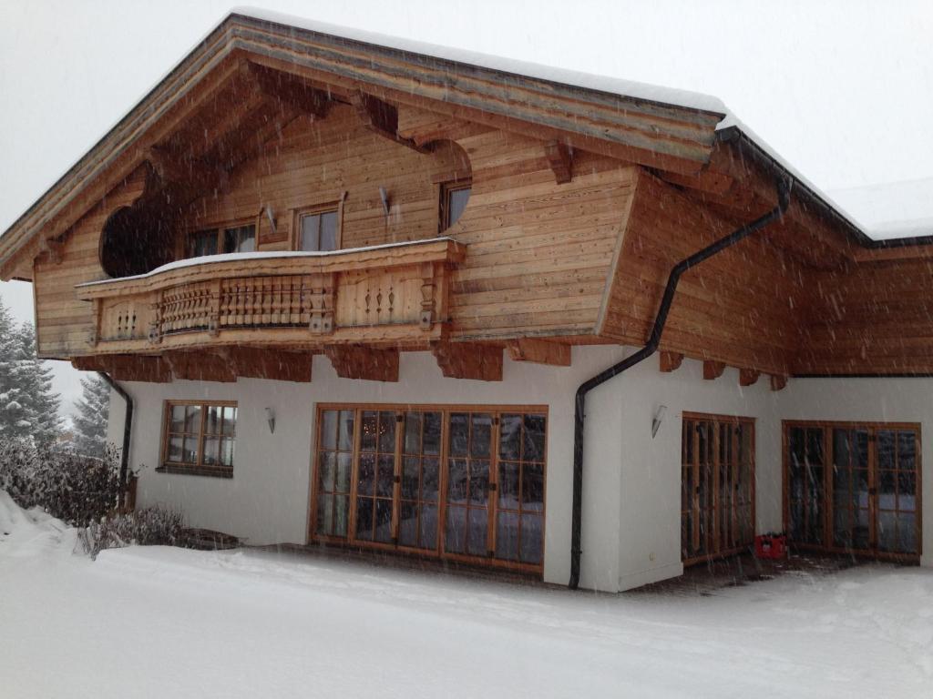 una casa con tetto in legno nella neve di Ado's Haus a Niederau