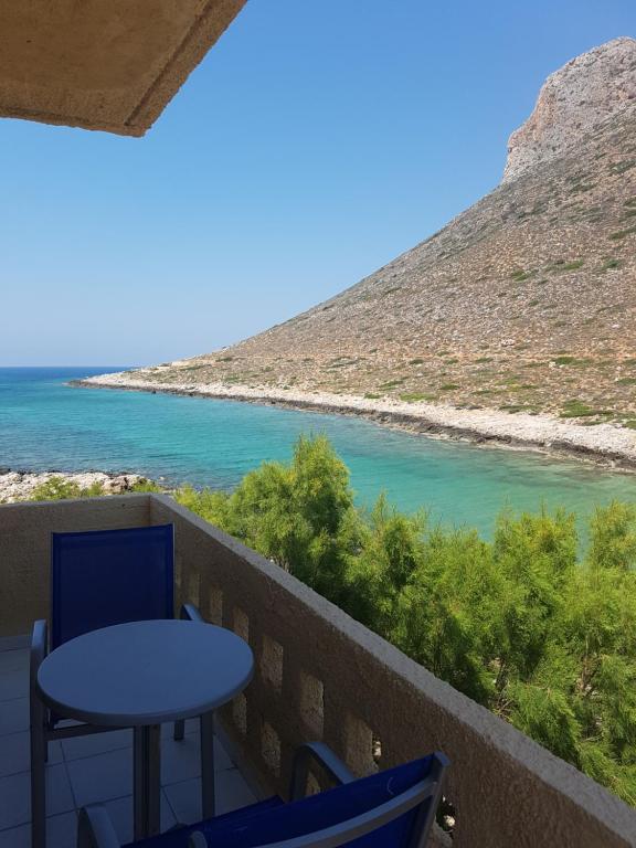 a table and chairs on a balcony overlooking the water at Little Bay in Stavros