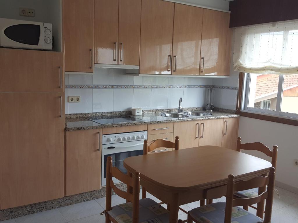 a kitchen with wooden cabinets and a table and a sink at Casa Artemia in Sanxenxo