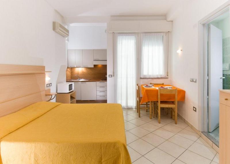 um quarto com uma cama amarela e uma mesa de jantar em Hotel Ferrara em Cattolica