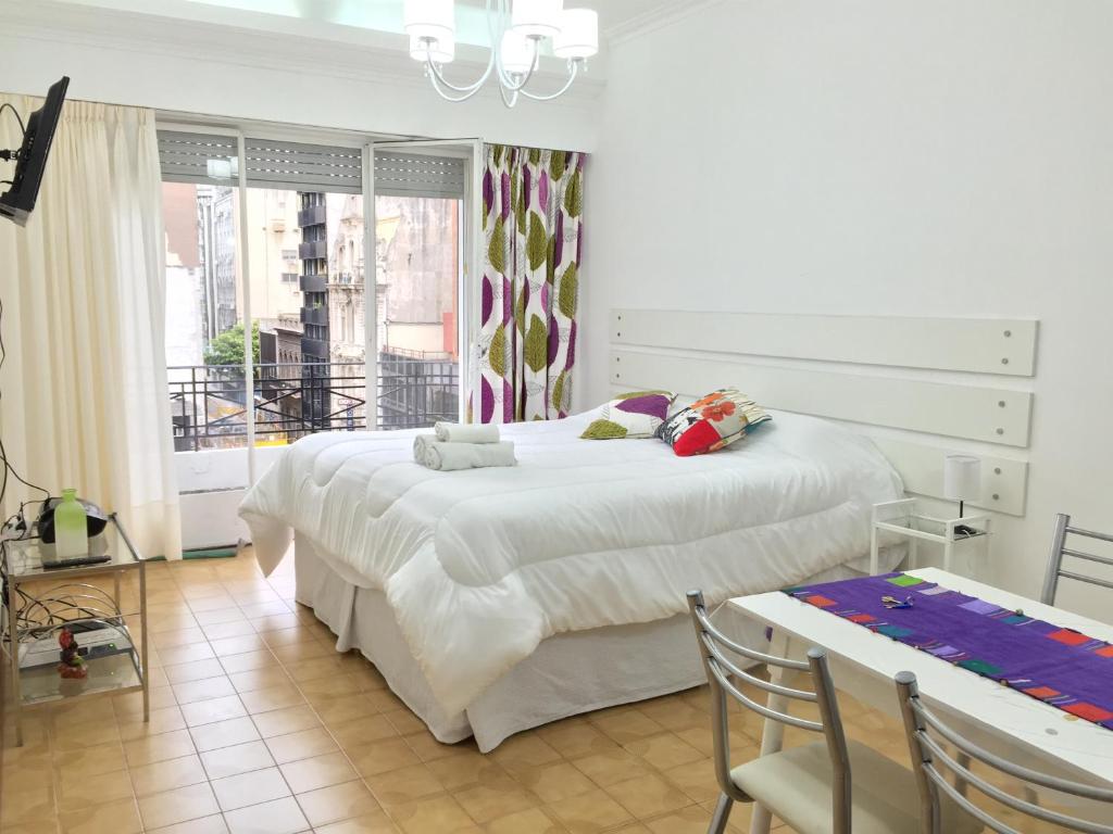 1 dormitorio con 1 cama grande, mesa y sillas en Barbara Suite Obelisco Best Location ig barbarasuites en Buenos Aires