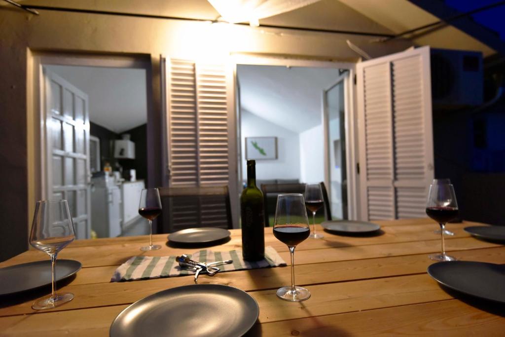 a wooden table with wine glasses and a bottle of wine at Apartmani Vinetan in Betina