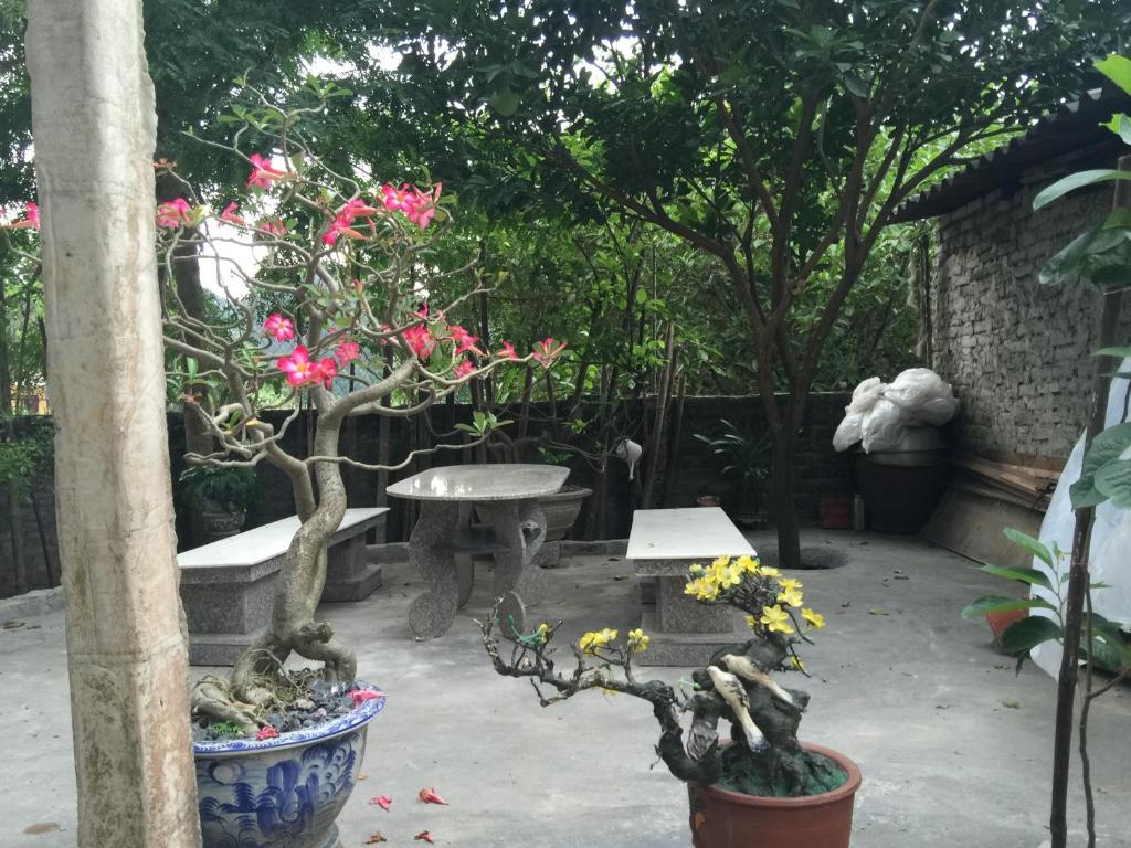 a garden with a table and some flowers and trees at Hung Anh Homestay in Ninh Binh
