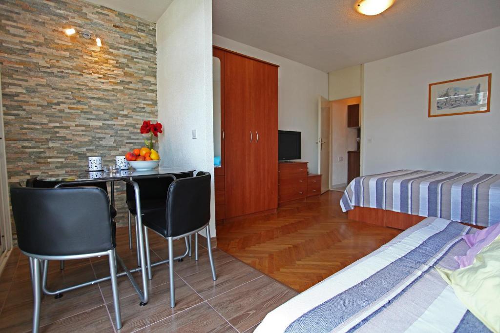 um quarto com uma cama, uma mesa e cadeiras em Apartman Great Wall em Split