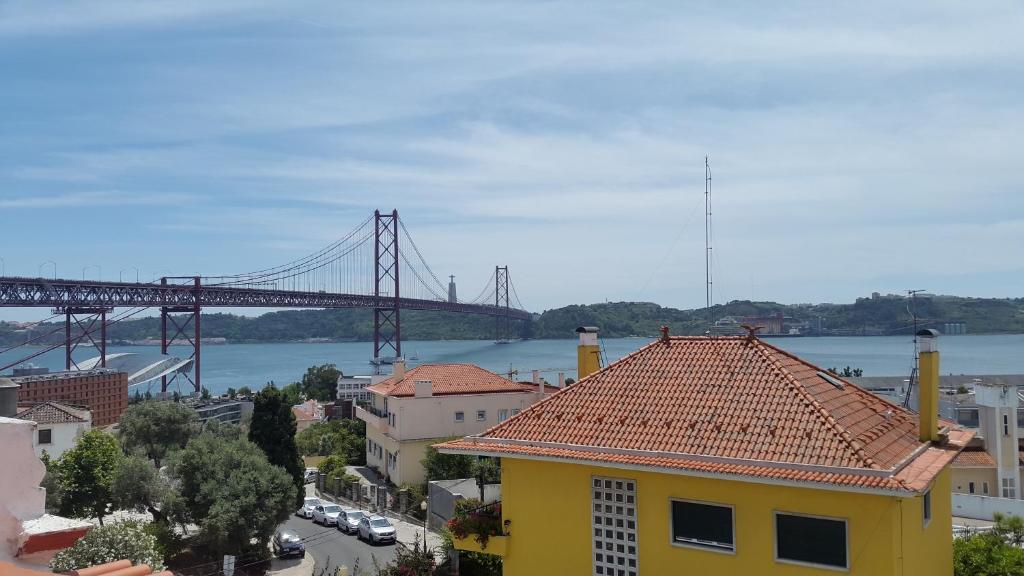 ein gelbes Gebäude mit einer Brücke im Hintergrund in der Unterkunft Apartamentos Tejo à Vista in Lissabon