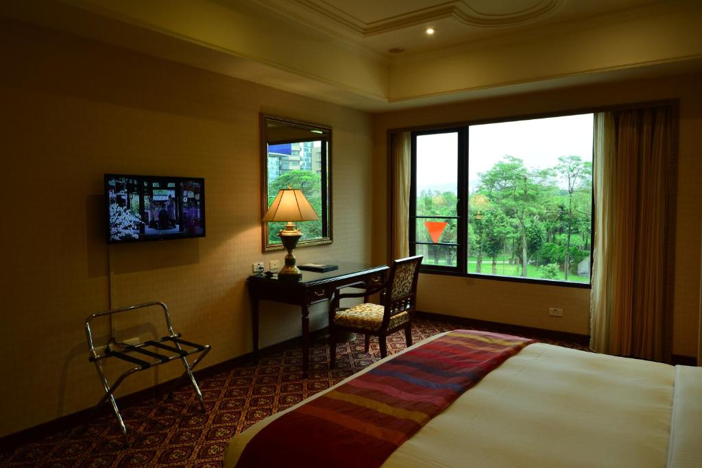 a hotel room with a bed and a desk and a window at Rido Hotel in Taipei