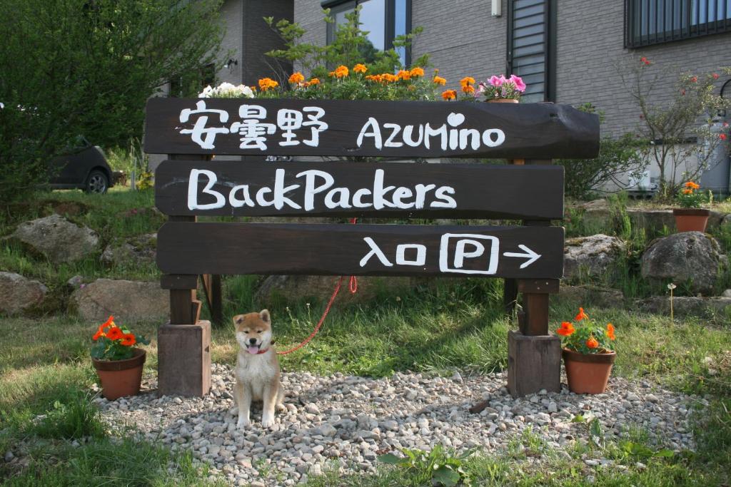 un chien en laisse debout sous un signe dans l'établissement Azumino Backpackers, à Matsukawa