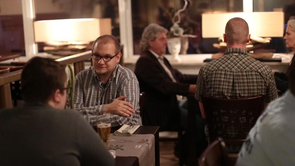 een groep mannen die rond een tafel in een kamer zitten bij Hotel am Bahnhof in Stendal