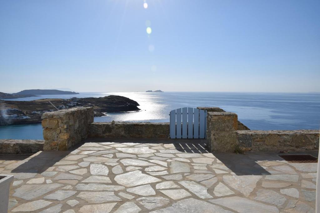 un banco sentado en un patio de piedra con vistas al océano en Andromeda Mykonos Villas & Suites en Kalo Livadi