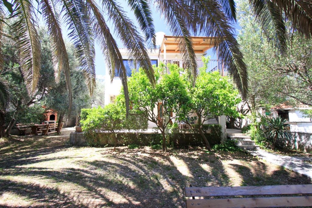 a house with palm trees in front of a yard at Apartments Dajana in Orebić