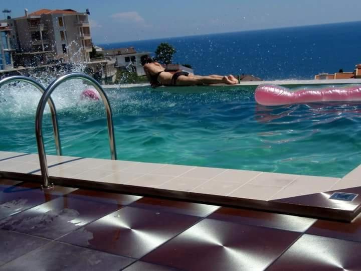 a man laying in a swimming pool with alatable at Apartments Monte in Ulcinj