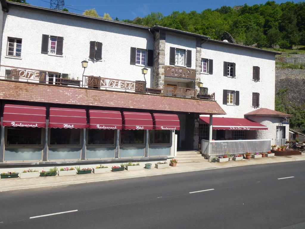 un edificio con toldos rojos al lado de una calle en Hôtel Restaurant Le Pain de Sucre, en Monistrol-dʼAllier
