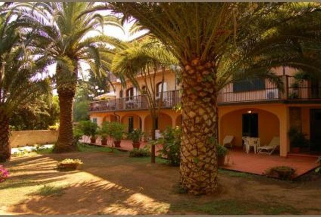 un edificio con palmeras delante en Albergo Belvedere en Porto Santo Stefano