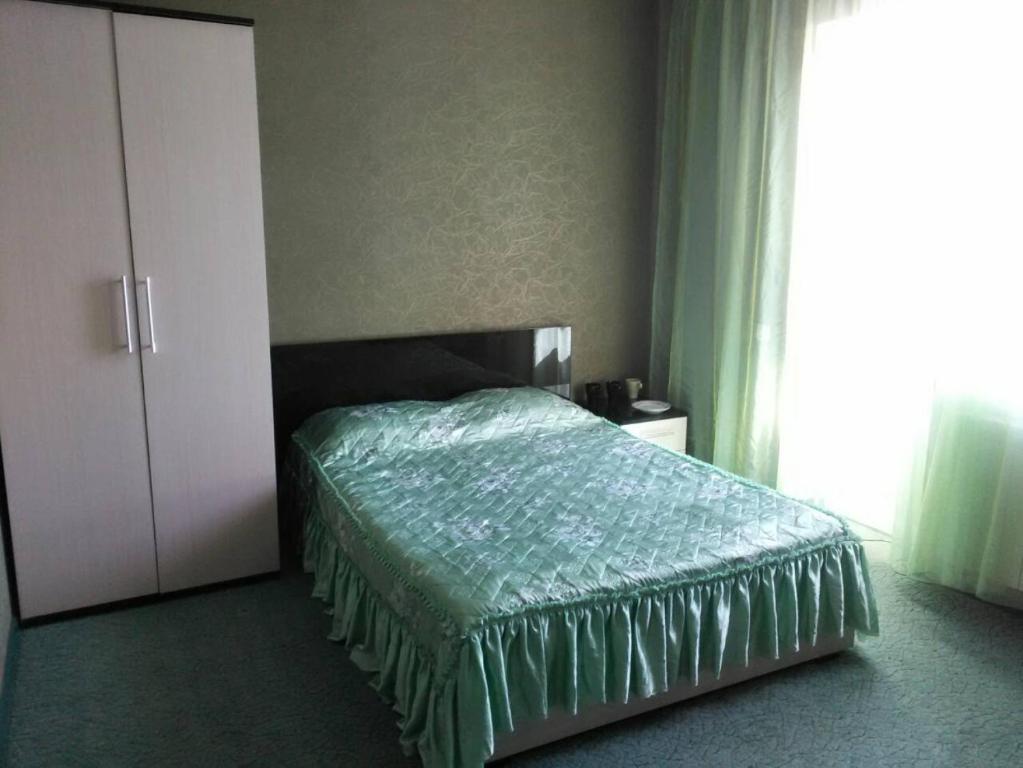 ゲレンジークにあるGuest House on Krasnodarskayaのベッドルーム1室(緑色のベッドカバー付)、窓が備わります。