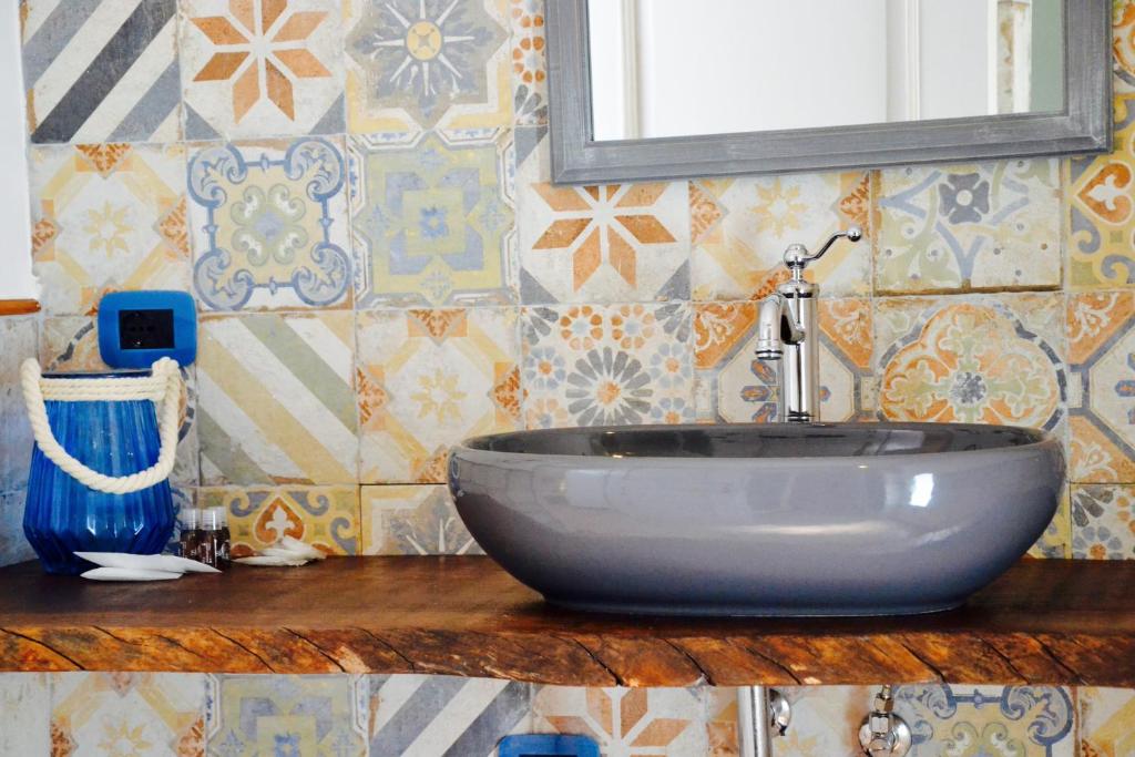 a bathroom with a sink and a mirror and tiles at Il Bottone al Duomo in Gaeta