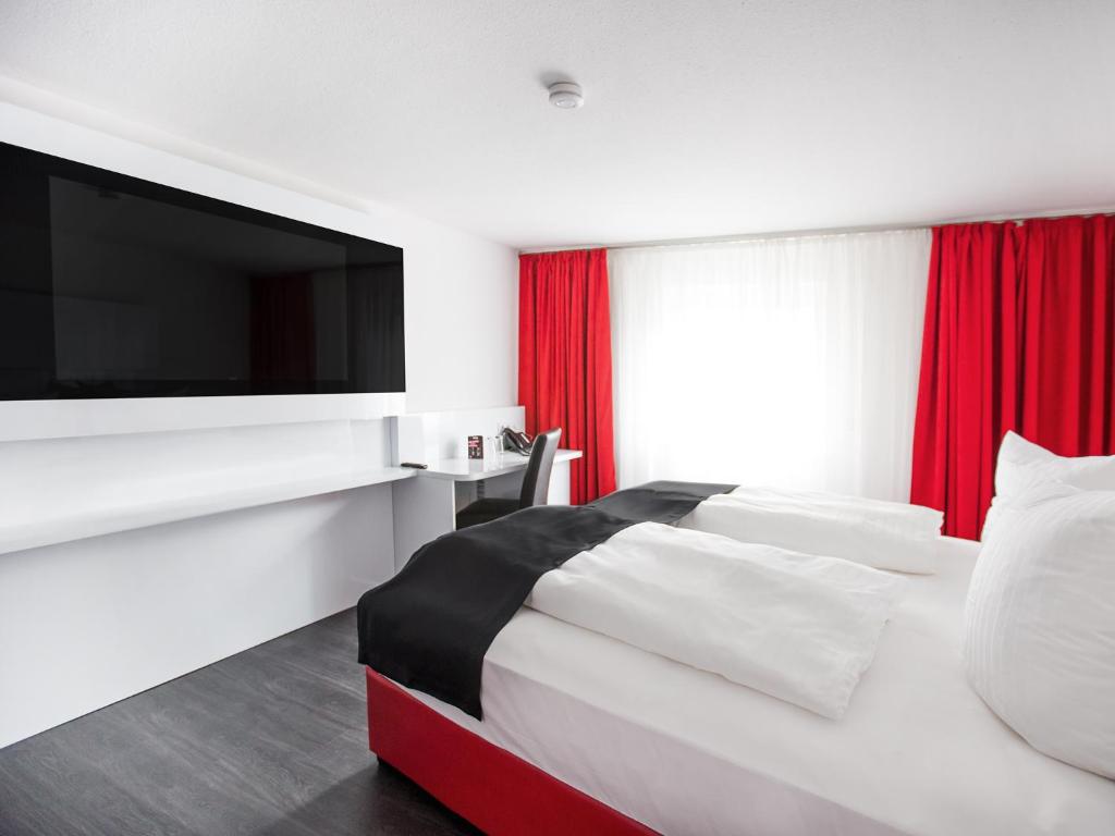 um quarto de hotel com uma cama e uma televisão de ecrã plano em DORMERO Hotel Villingen-Schwenningen em Villingen-Schwenningen