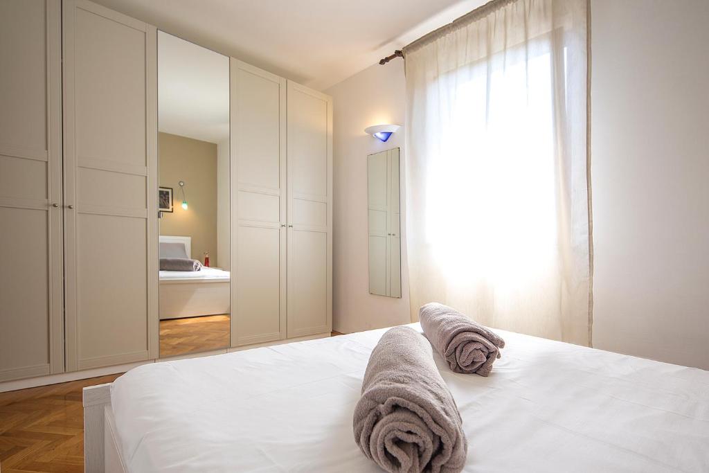una camera da letto con un letto bianco e asciugamani di Apartments Bo a Malinska