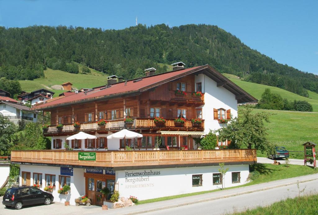 ein großes Holzgebäude mit Balkon auf einem Hügel in der Unterkunft Gästehaus Bergstüberl in Reit im Winkl