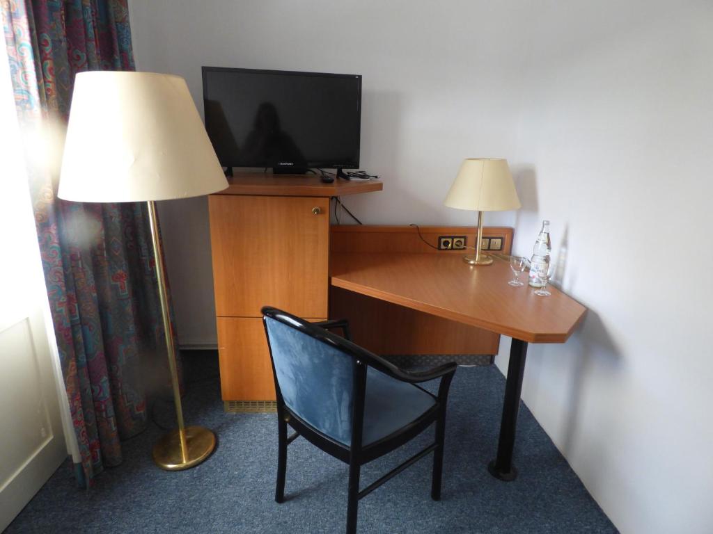 a room with a desk with a television and a lamp at Pension Seeterrasse in Serwest