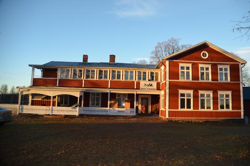 a large wooden house with a porch on a street at Husby Wärdshus in Dala Husby
